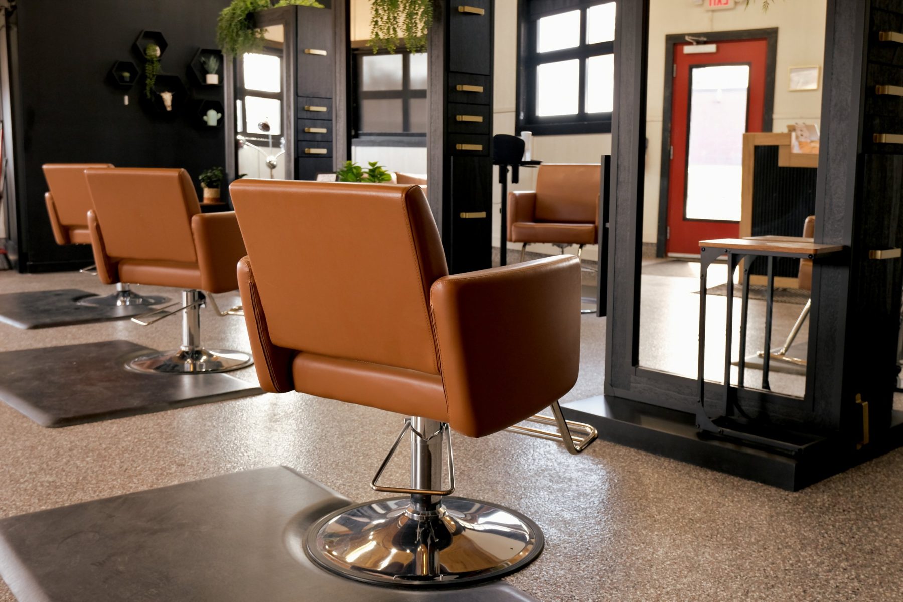 A hair salon interior with styling chairs and a long bar of warm light