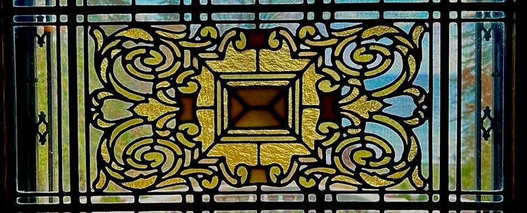 A stained glass panel with a gold scrolling medallion